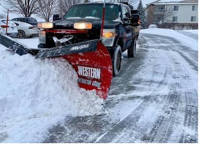 Crew member in high-visibility gear operating a snow blower